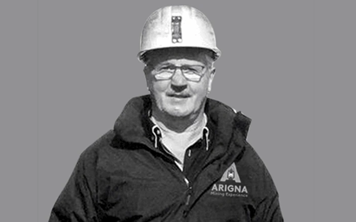 Man wearing a hard hat and jacket with the Arigna Mining Experience logo, promoting guided underground mine tours.